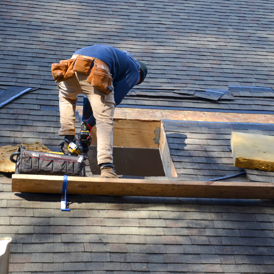 A roofer works around a new cut-in on a residential roof